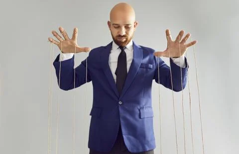 Man in suit pulling strings of puppet. Stock Photos