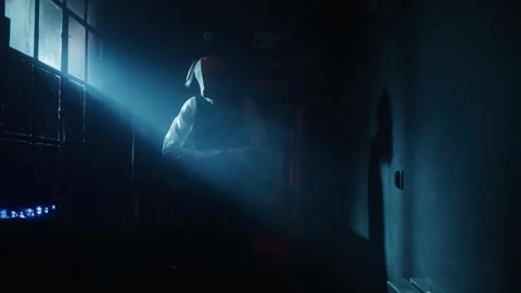 A man in a suit with rabbit mask walking in the corridor lit by blue side lig Video stock 259010277