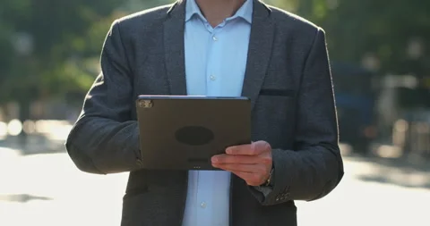 A man in a suit raises an electronic tablet in front of him. Stockbeeldmateriaal 161083751