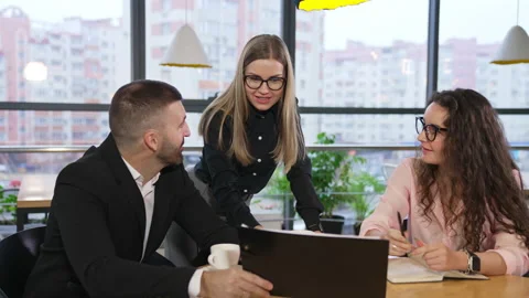 Man in suit sits in front of his colleagues showing them papers in black folder. Stock Footage 196502022