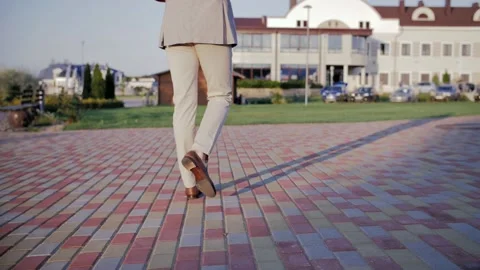 A man in a suit slowly walks down the sidewalk. Men's shoes (slow motion) Stock Footage 221628378
