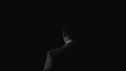 Man In Suit Standing With Back To Camera Against Dark Background Видео 336542194