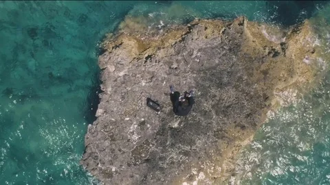 Man in suit stranded on a deserted rock in the middle of the ocean Stock Footage 77917645