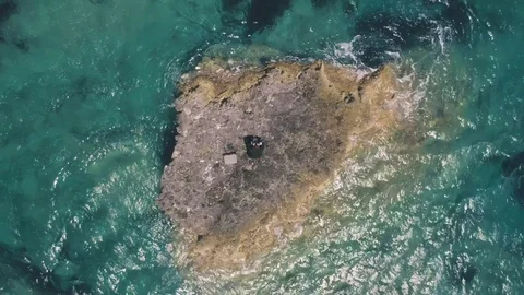 Man in suit stranded on a deserted rock in the middle of the ocean 動画素材 77919621