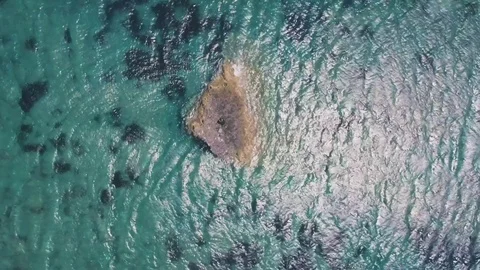 Man in suit stranded on a deserted rock in the middle of the ocean Stock Footage