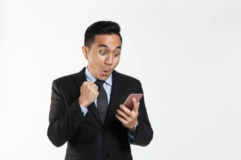 Man in suit with surprise expression while looking at his phone Stock Photos