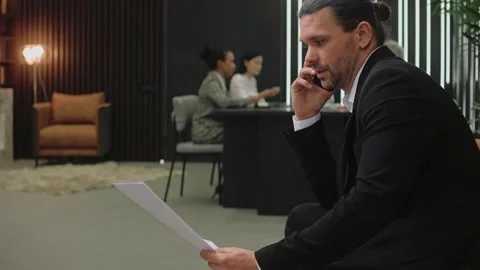 Man in suit talk on the phone while employees sit at meeting in modern office Vídeo Stock 166968762