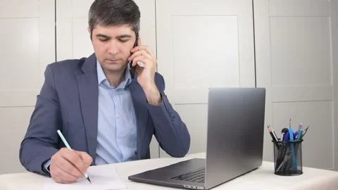 Man in suit talking on the phone and taking notes Stock Footage 169725896