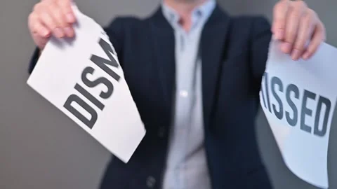 A man in a suit tears a notice labeled dismissed in two parts. He appears to be Stock-Footage 338299570
