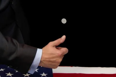 A man in a suit tosses up a 5-cent coin with his hand on a dark background 写真素材