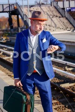 Man in suit at train station looking at his wristwatch Stock Photos