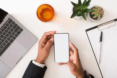 Man in suit using blank smartphone on workplace desk Stock-Fotos