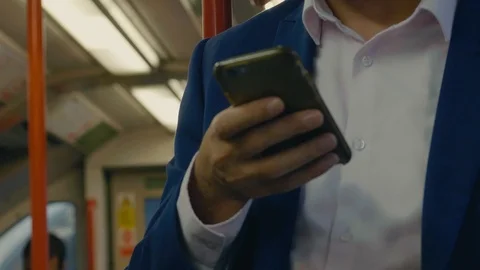 A man in a suit using mobile phone on the London underground tube train Stock Footage 88955704