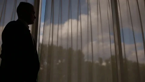 Man in suit walking in front of the big window Stock Footage 79789957
