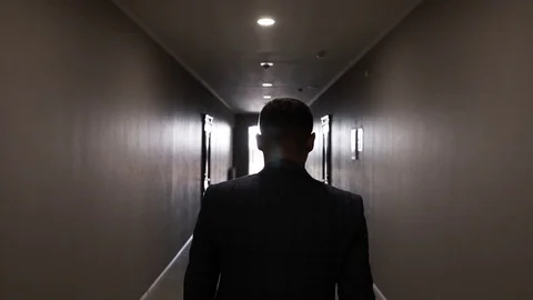 A man in a suit walks along the long and empty corridor of the hotel Stock Footage 129260221