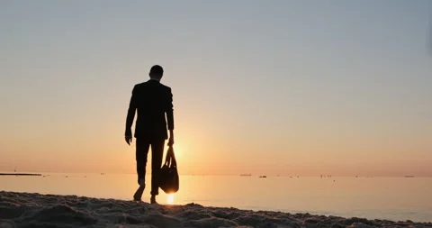 A man in a suit walks out onto the beach Video stock 145890331