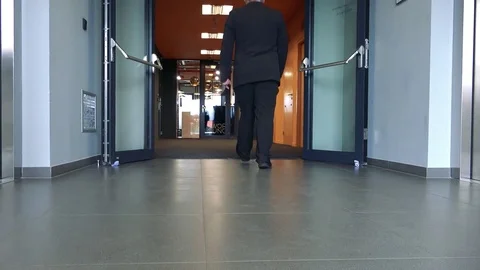 A man in a suit walks out of an elevator through a corridor into a work lounge - Video stock 79571557