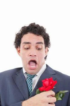 Man in suit with weird face expression holding with his hand rose Stock Photos