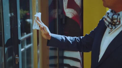 A man in a suit wipes the door handle before entering Vidéo 201756080
