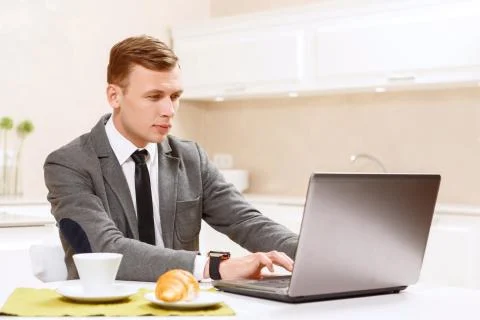 Man in suit working on computer kitchen Foto stock