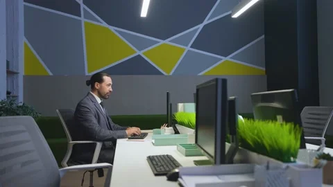 A man in a suit works at a computer in an empty office, makes analysis, reports Stock Footage 233994891