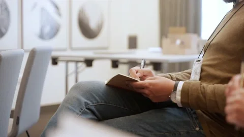 Man in a suit writing down notes from a seminar, sitting on a chair Video stock 218615603