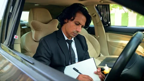 Man in suit writing in notebook inside car Stock Footage 277035427