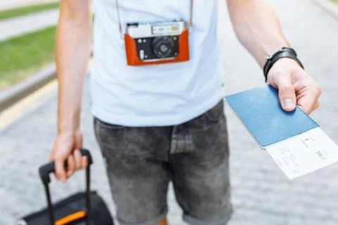 A man with a suitcase and a camera, holding a passport and tickets close-up Stock Photos
