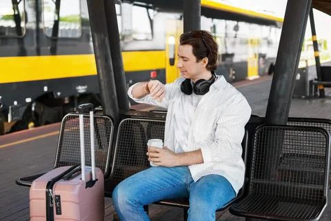 Man with a suitcase checking his watch on a railway platform. He awaits eco.. Stock Photos
