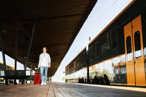 Man with a suitcase on a railway platform by a train, highlighting eco tran.. Stock Photos