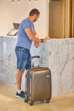A man with a suitcase stands in front of the reception Stock Photos