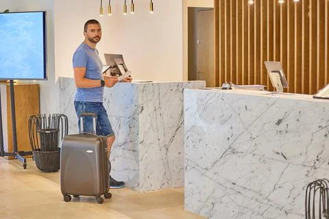 A man with a suitcase stands in front of the reception Stock Photos