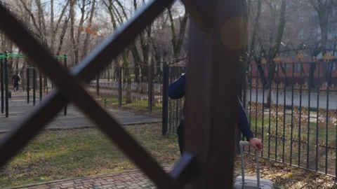 Man with a suitcase talking on a phone behind a wooden structure Stock Footage 331460951