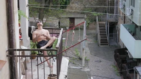 Man sunbathing on the balcony Stock Footage 195052022