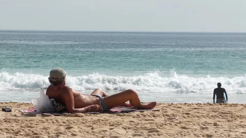 Man sunbathing on the beach with his legs spread Video stock 294673226