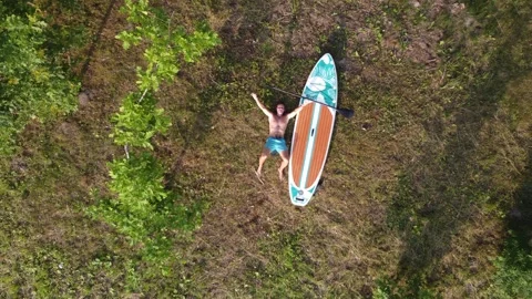 A man is sunbathing with a sup board on an island in the lake. Stock-Footage 246294556