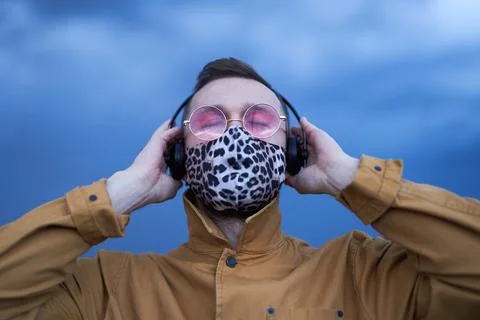 Man in sunglasses and leopard pattern mask listening music Stock Photos