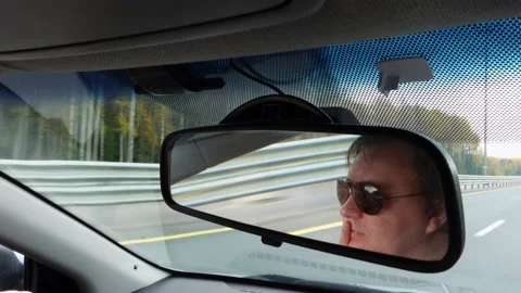 Man in sunglasses drives car on empty road close mirror view Video stock 205770788