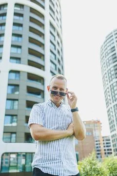 Man with sunglasses posing outside modern buildings in a city during the day Stock Photos