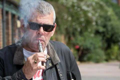 Man in sunglasses puffing on an e-cigarette Stock Photos
