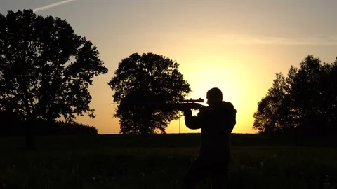 Man on a sunset background with gun slow Stock Footage 80326724