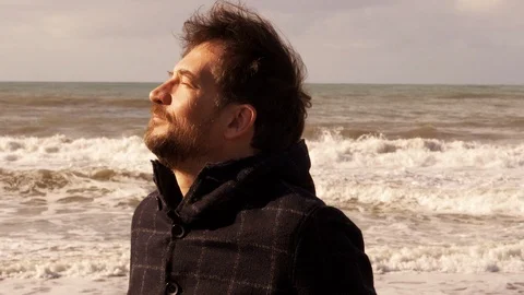 Man at sunset enjoying sun than looking camera in front of the ocean slow mot Stock Footage 115590966