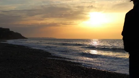 Man at sunset searching for seashells on the beach at The Black Sea. 動画素材 126702219