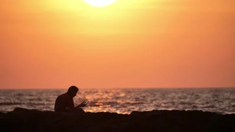 Man at sunset sitting on the phone Stock Footage 264085778