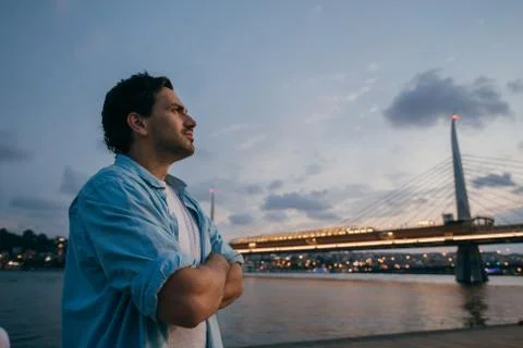 A man at sunset on the waterfront on the background of the city. Stock Photos