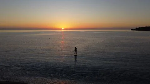 Man on a sup board at sunset Stock Photos