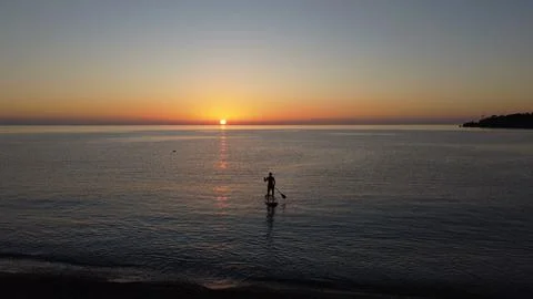 Man on a sup board at sunset Stock Photos