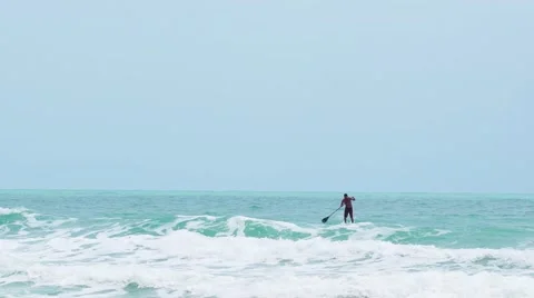 Man on sup borad riding the waves in a sea storm. Slow motion Stock Footage 63177832