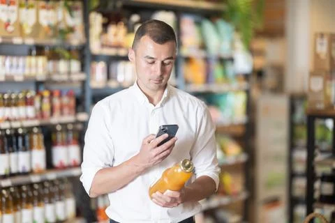 Man in supermarket scan QR code on bottle of drink Stock Photos
