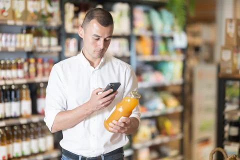 Man in supermarket scan QR code on bottle of drink Foto stock